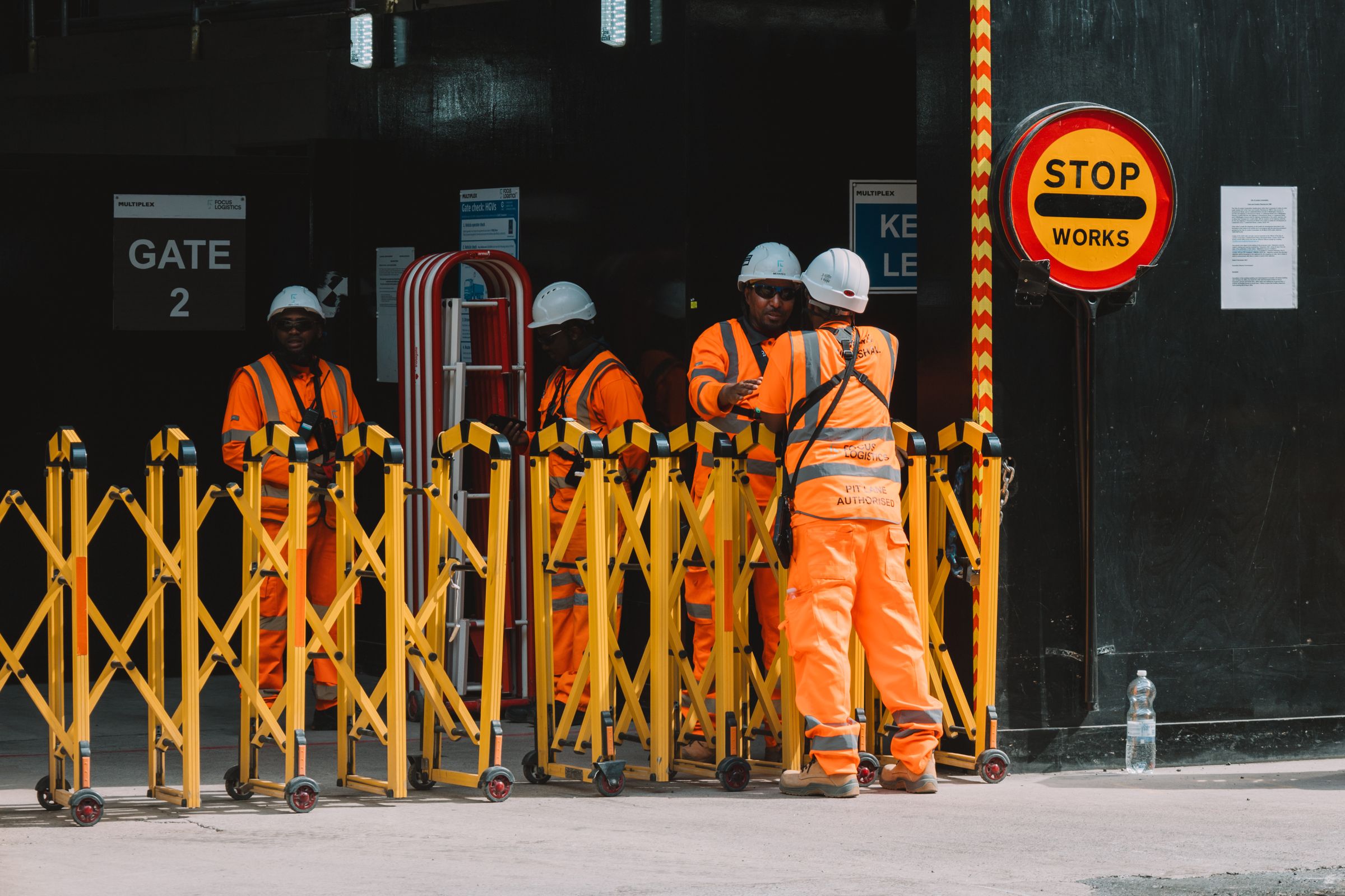 Construction workers in orange hi-vis at a London site entrance